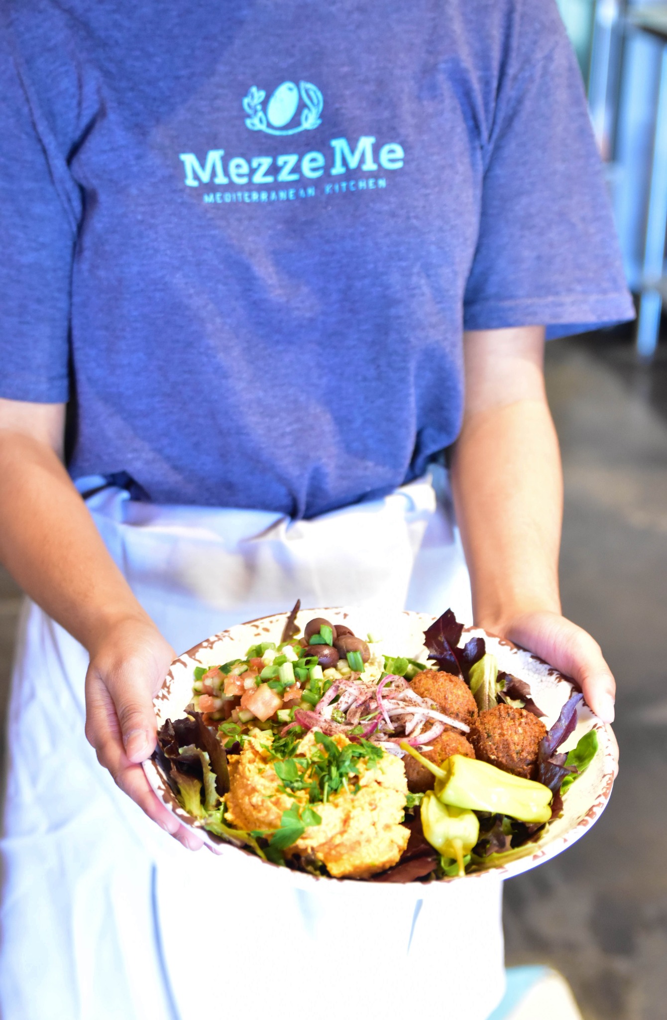 A MezzeMe team member presenting a freshly prepared meal